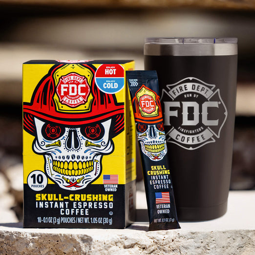 A lifestyle image of the On The Go Bundle featuring a box of Skull-Crushing Instant Espresso Coffee and a 20oz FDC black tumbler on a slab of broken concrete.