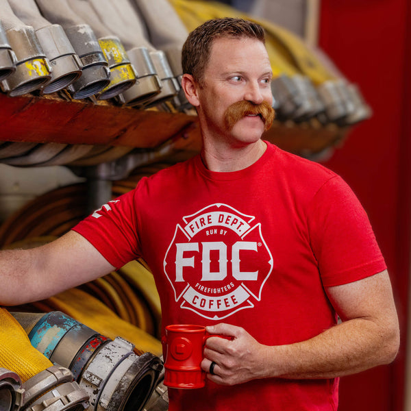 A red Fire Department Coffee T Shirt, featuring FDC's maltese cross logo in white.