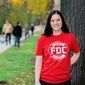 A lifestyle image of someone wearing the Fire Department Coffee Red Shirt. The front of the shirt features the FDC maltese cross logo in white.