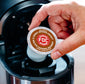 Hand inserting a Salted Caramel Bourbon Coffee pod into a coffee machine.