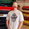 Man wearing a vintage white t-shirt with a black skull design wearing a fire helmet in a fire station 