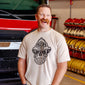 Man wearing a vintage white t-shirt with a black skull design wearing a fire helmet in a fire station 