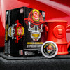 A box of Skull-Crushing Espresso Coffee Pods resting on the front of a fire truck next to a Hydrant Mug.