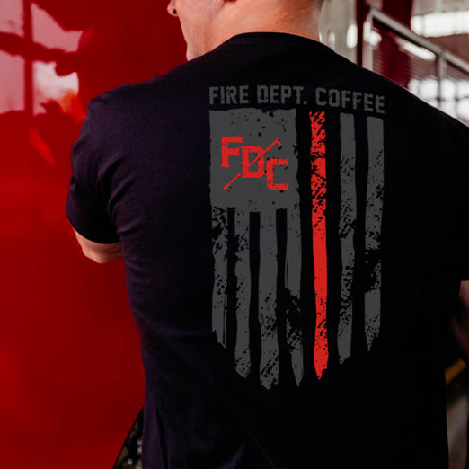 A lifestyle image of someone wearing the Thin Red Line Shirt. The back of the shirt features the thin red line flag with the FDC pike pole logo and text that reads ”Fire Dept. Coffee”