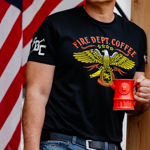 A lifestyle image of someone wearing the US Eagle Shirt. The front of the shirt features a US eagle design with text that reads ”Fire Dept. Coffee”.