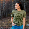 A lifestyle image of the Wildland Firefighter Skull Shirt. The front of the shirt features a skull design with wildland firefighter inspiration. The text around the skull reads, "Fire Department Coffee"