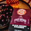 A bag of Black Cherry Bourbon Infused Coffee sitting next to a bowl of cherries