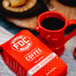 A bag of Original Medium Roast Coffee laying on a table next to a Fire Hydrant Coffee Mug full of coffee