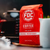 An image of FDC's Original Medium Roast Coffee resting on a table with various coffee brewing items around it.