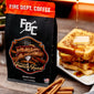 A 12 oz bag of Cinnamon French Toast Coffee from Fire Department Coffee on a table next to a plate of french toast.