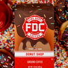 A 12 ounce package of Fire Department Coffee's Donut Shop Coffee surrounded by rainbow sprinkles and donuts.