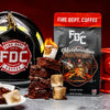 An image of FDC's Marshmallow Brownie coffee on a table next to a fire helmet, a pile of brownies, and toasted marshmallows. 
