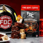 An image of FDC’s Marshmallow Brownie coffee on a table next to a fire helmet, a pile of brownies, and toasted marshmallows. 