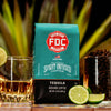 An image of FDC's Tequila Infused Coffee next to a shot of tequila and a glass of roasted coffee beans. 
