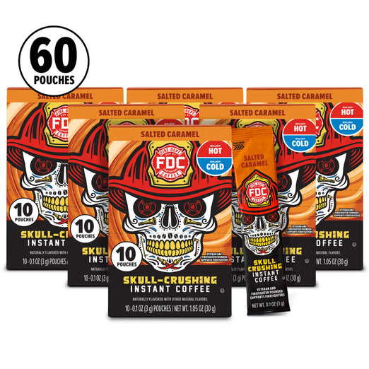Six FDC Firefighter Salted Caramel Instant Coffee pouches arranged in a fan shape, with a black circular ’60 POUCHES’ badge in the top left corner. The packaging features a bold skull wearing a firefighter helmet design in orange, black, and red.