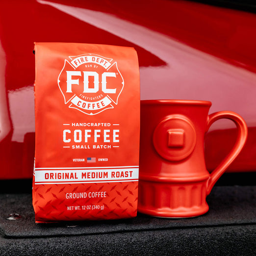 Original Medium Roast and a Hydrant Mug resting on the front of a fire truck.
