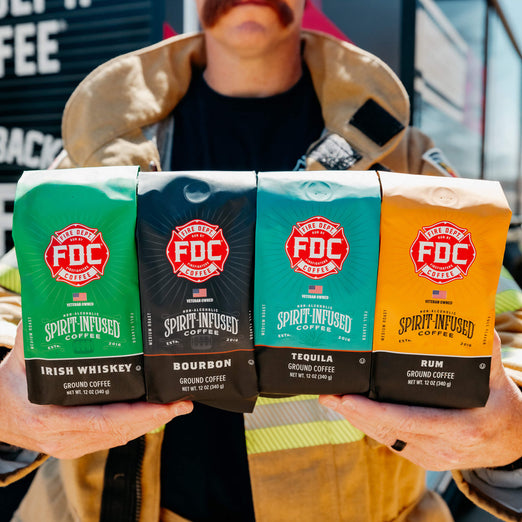 A firefighter holding up the four coffees included in the Spirit Infused Coffee Bundle.