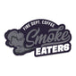 Black sticker with grey and white lettering that says ”Fire Dept. Coffee Smoke Eaters” with a smoke design.
