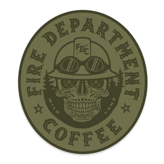Olive green sticker with ”Fire Department Coffee” around the edge of the oval. There is a skull in the middle wearing a firefighting helmet
